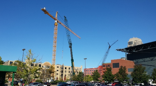 Cranes working on Arena Place tower over a nearby parking lot