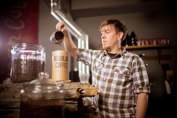 Stephen Curtis pours beans into a coffee canister.