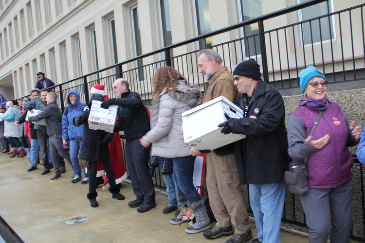 A chain of volunteers deliver boxes and boxes of completed petitions to the state.