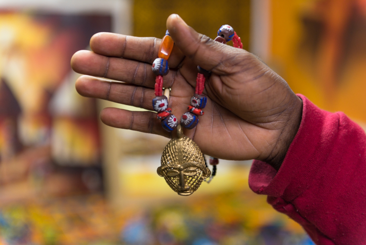 Tacitus Bailey-Yabani holds one of the necklaces he sells at Abeshi. Photo by Jenna Swartz