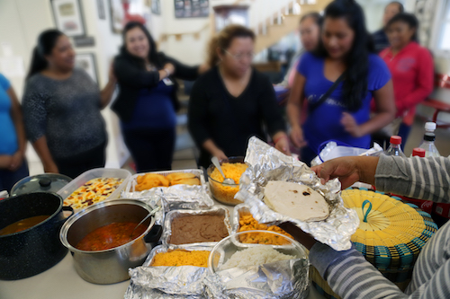 Las invitadas se ponen en fila para servirse un plato de comida.
