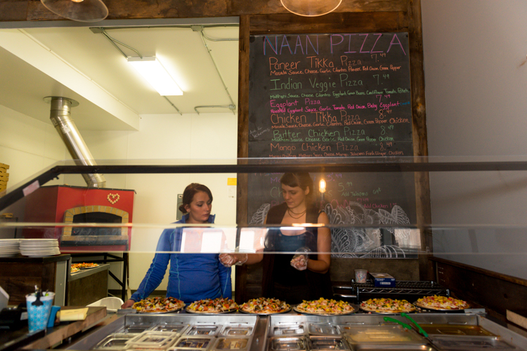 Tessla Smith, left, and Amber Brown prepare pies for the dinner rush hour at Naan Pizza.
