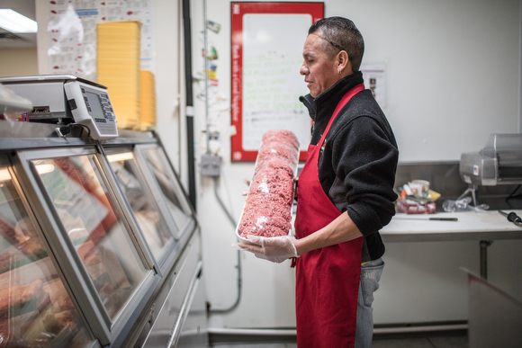 Sergio Bautista attending to a client behind the meat display at Supermercado Bedolla. 