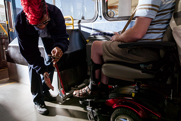 Ebony Fields helps David Covey get secured on a Rapid bus.