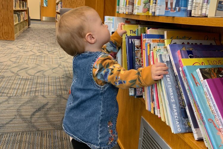 Ceci Davis, 2, evaluates the children's collection at the Yankee Clipper branch of the Grand Rpids Public Library.