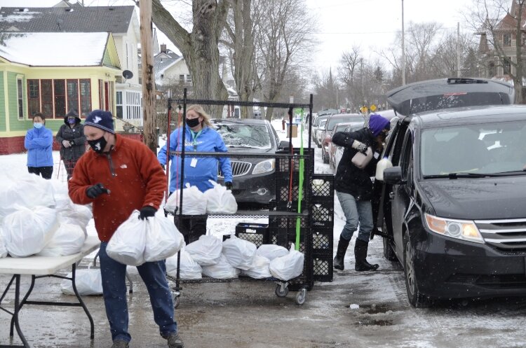 Muskegon YMCA volunteers distribute bags of food to those in need.