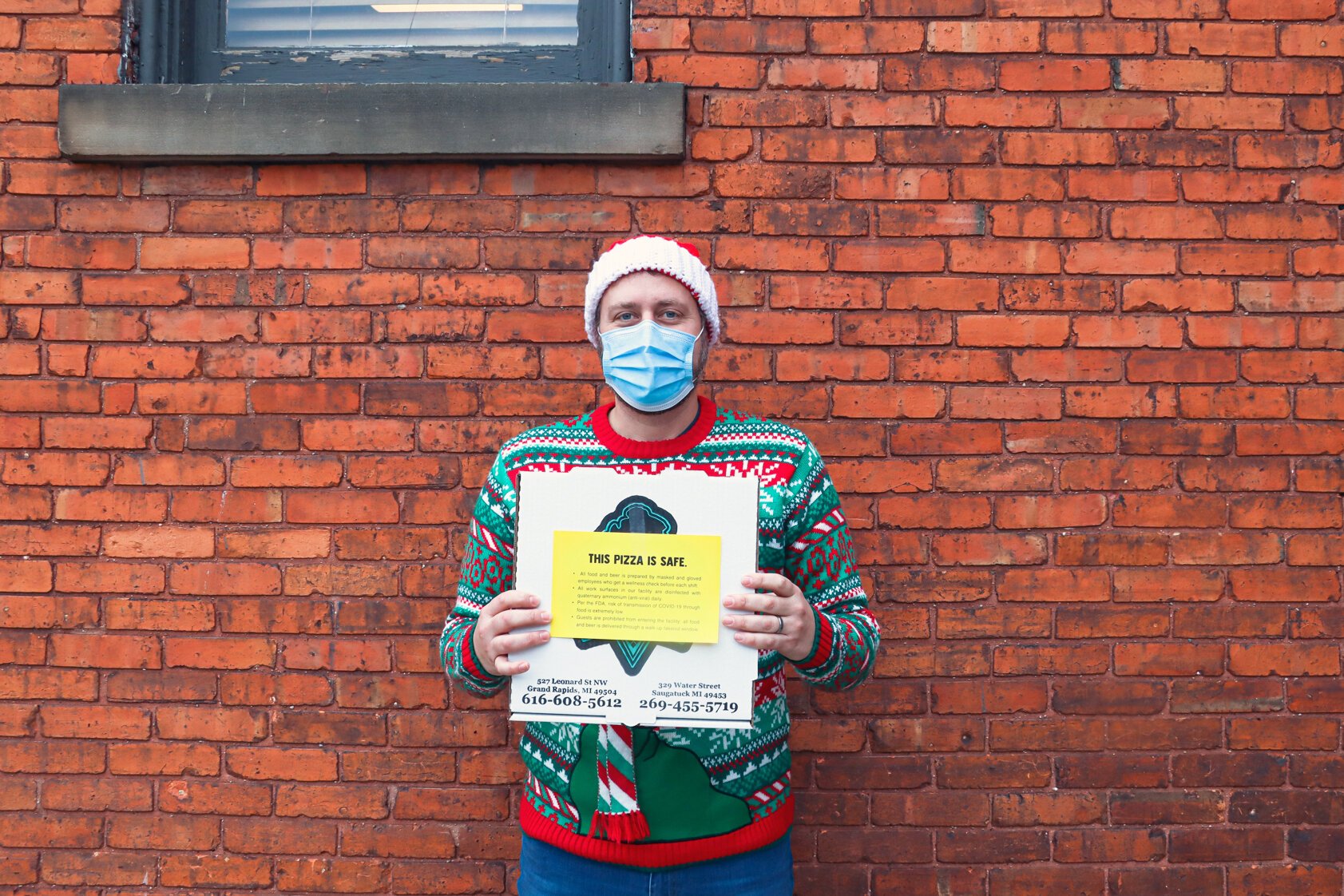 Chris Andrus of The Mitten Brewing holding This Pizza is Safe campaign