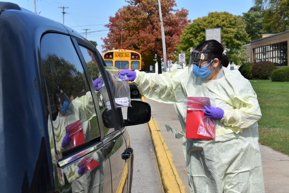Staff collect a saliva sample curbside at a Godfrey Lee school. Image courtesy School News Network.