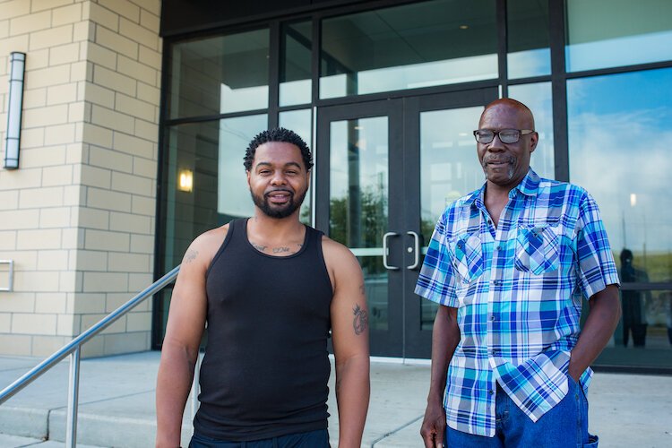 ICCF residents Mike, left and Jimmy, right unload food and supplies outside the nonprofit's residential housing facility on Stockbridge.