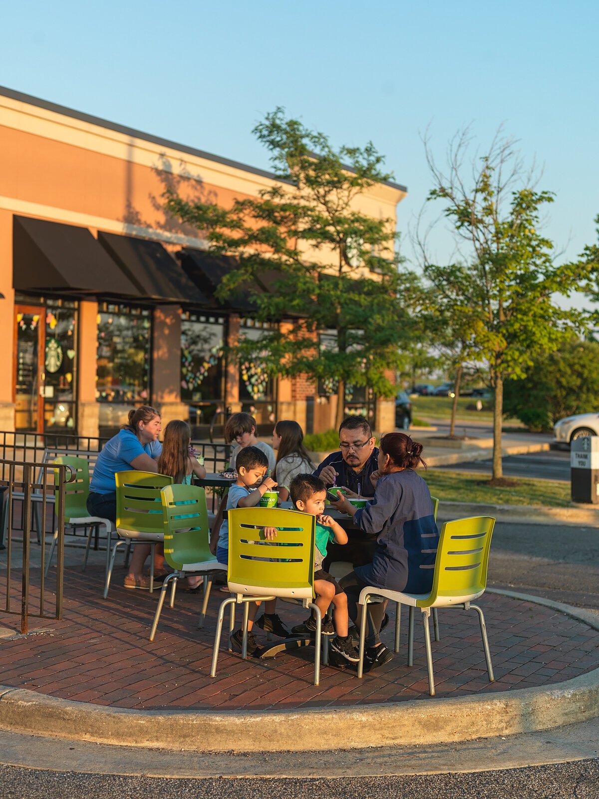 A few families enjoy the evening while sitting distanced apart outside at Peachwave Frozen Yogurt & Gelato.