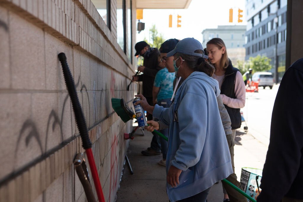 Volunteers work together to clean graffiti on the walls of the GRPD.
