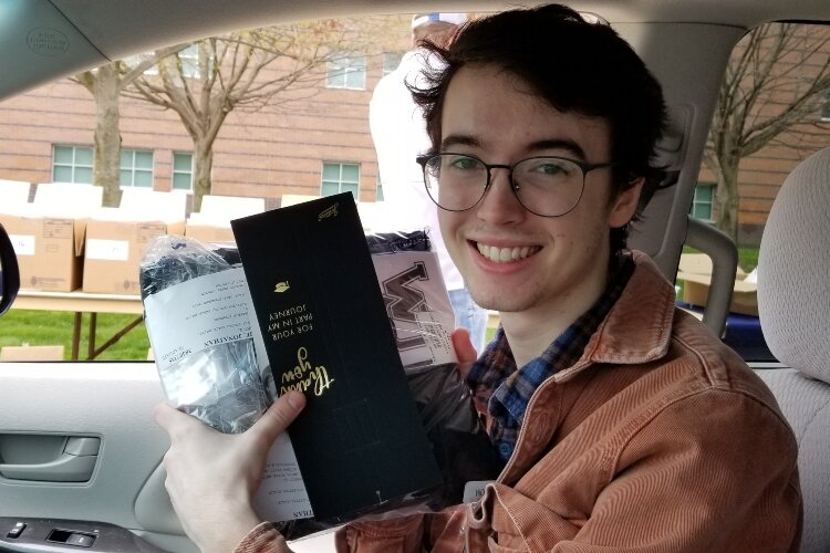 Jonathan McCabe smiles after picking up his cap and gown in the drive-thru line as West Ottawa teachers and staff cheered students.
