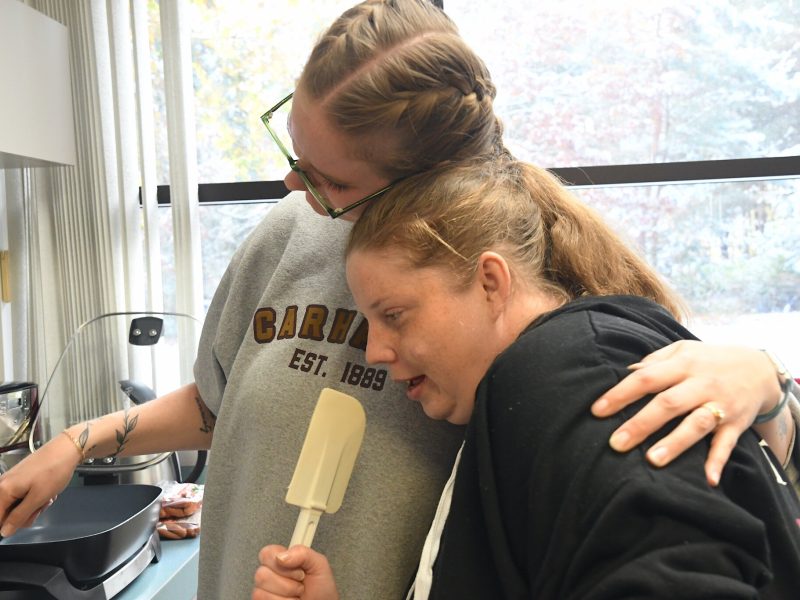 Natalie Visser, an assistant supervisor for MOKA, left, and Tracy share a warm embrace during a life skills session on cooking at a MOKA site in Wyoming.